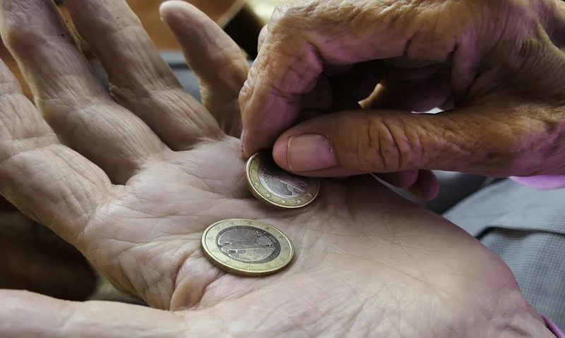 Mano de anciano con dos euros